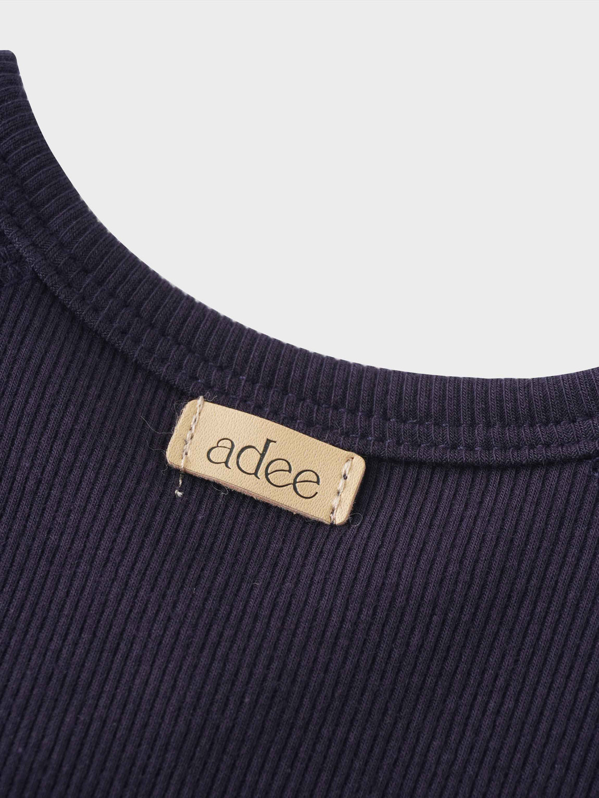 Navy crossover thin ribbed pajama fabric with beige stitched adee label at neckline.