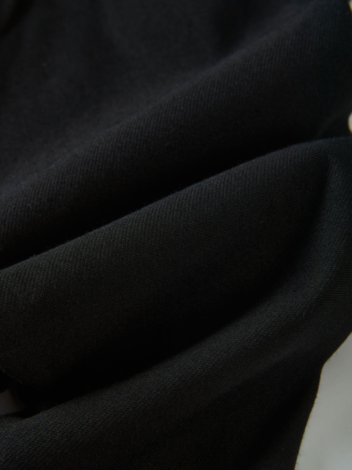 Denim overalls in black by Adee; close-up of textured fabric with gold button detail and visible stitching.