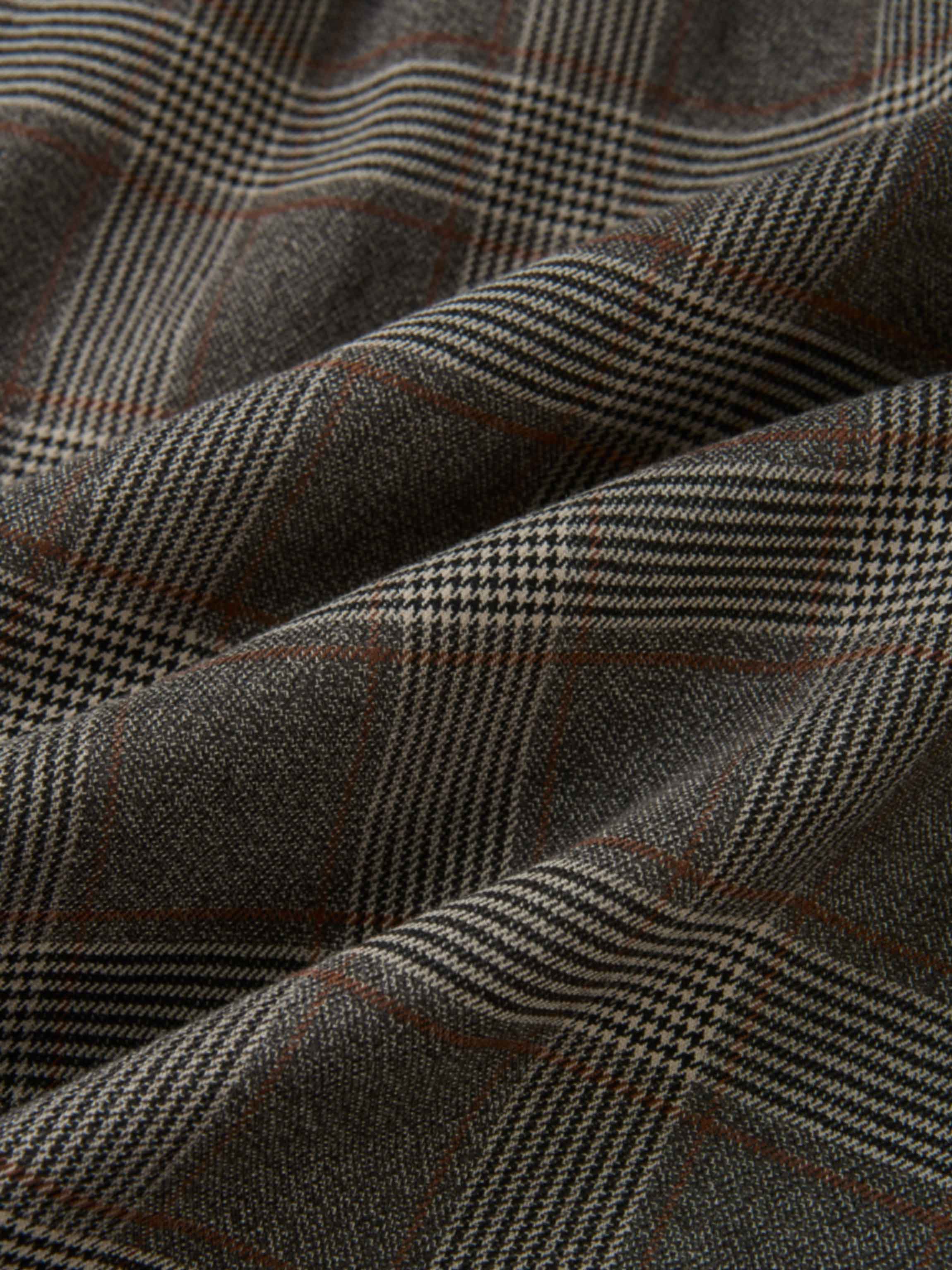 Plaid dress fabric in grey with small checks and brown accents.