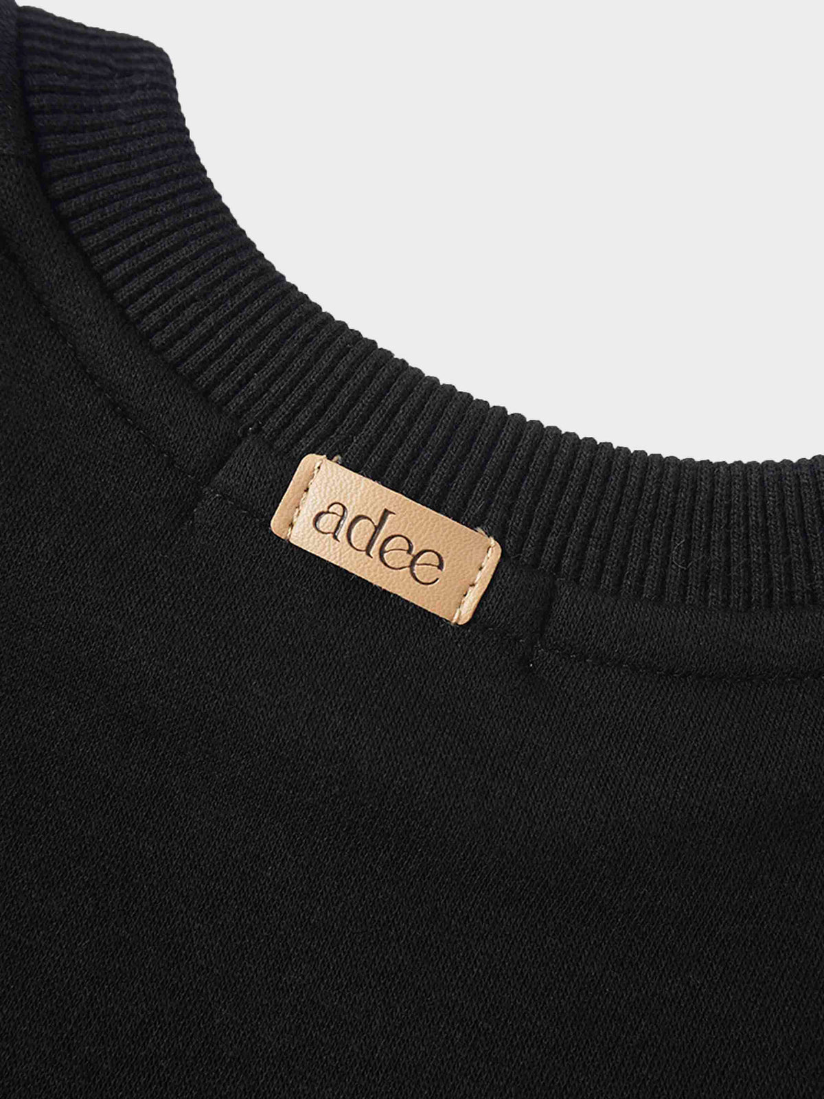 Black Skyline Sweatshirt collar detail with ribbed crew neck and tan brand tag.