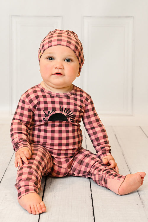 Baby girl in pink gingham stretchy footie with sun embroidery and Adee on front, inseam zipper.