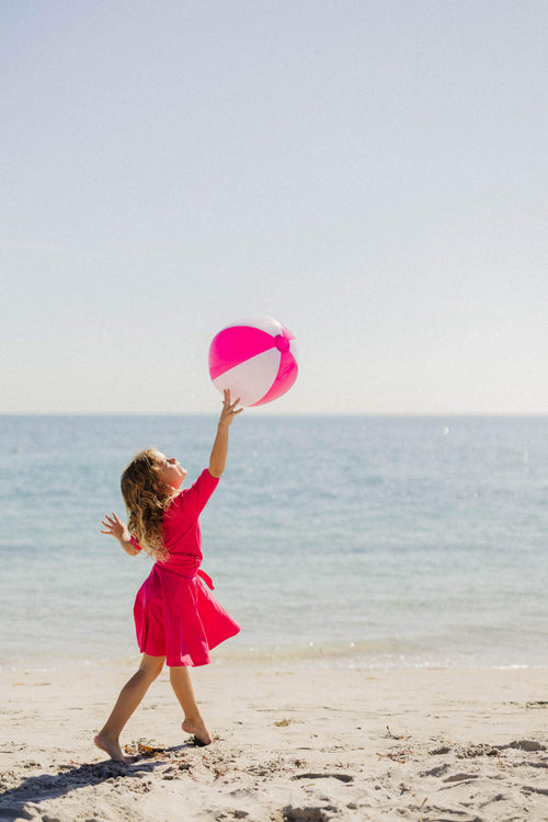 Girl in pink skirt playing beach ball