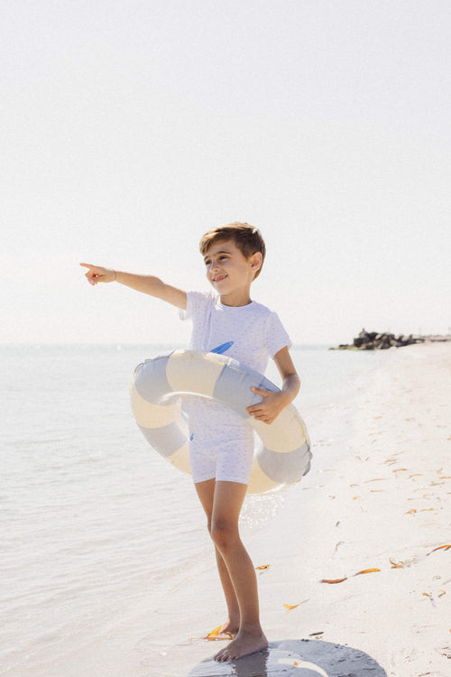 Boy in beachwear with float