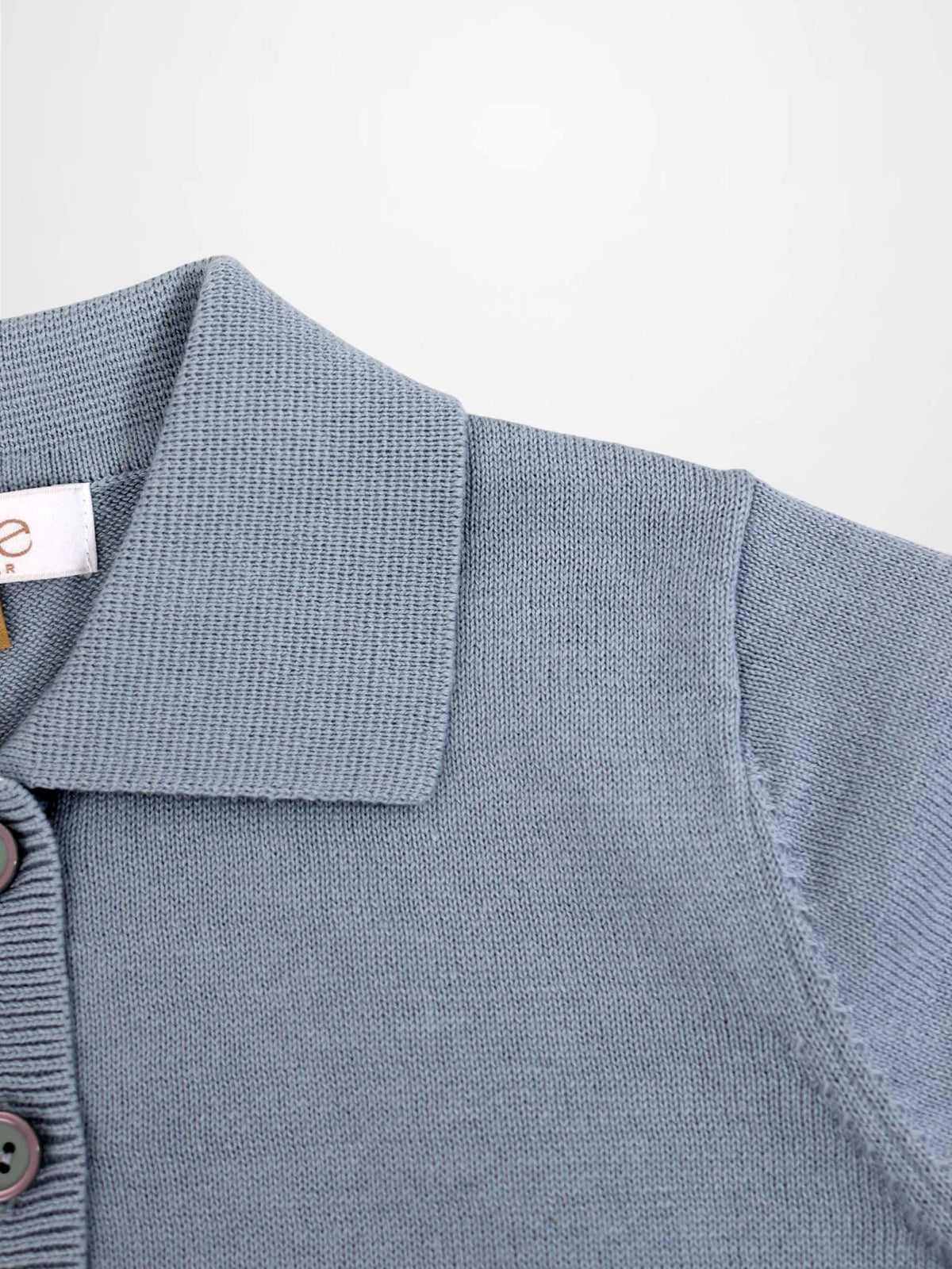 Light blue knit sweater with polo collar and button placket, close-up knit texture.