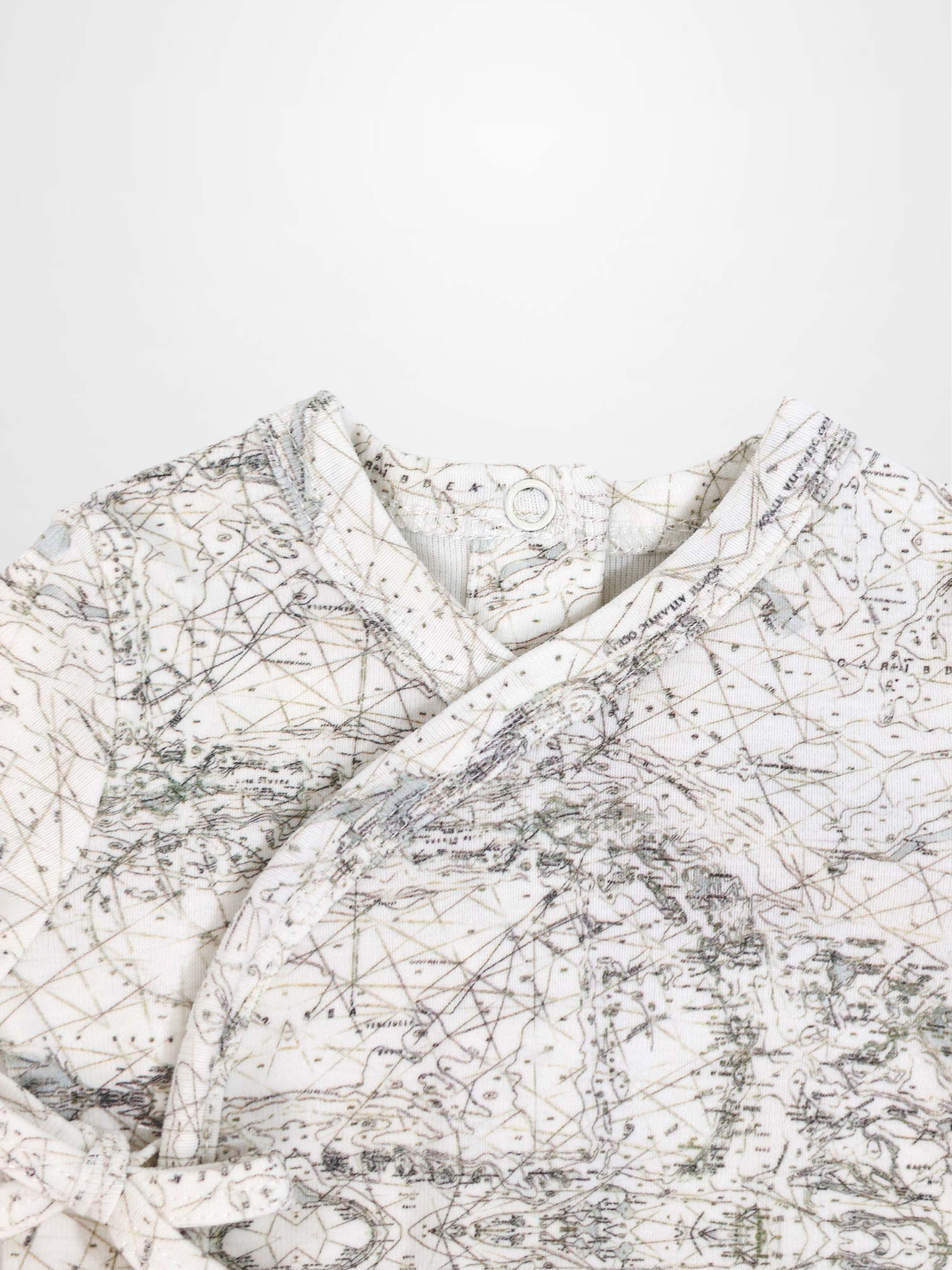 Map Stretchy baby jumpsuit footie with sage-green map lines, compass markers on off-white fabric.