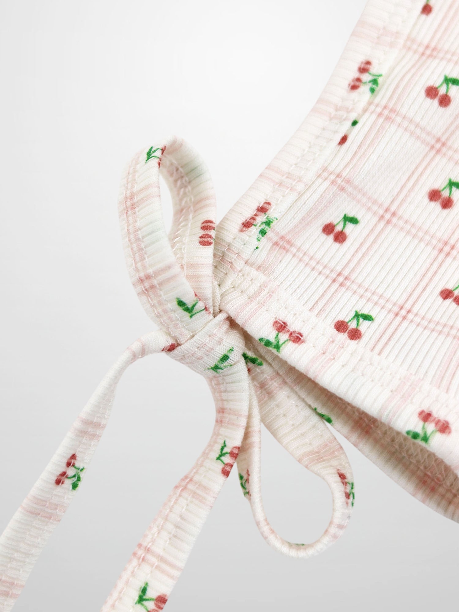 Cherry Window Bonnet for girls by Adee; pink-and-white thin-ribbed knit with cherry print and tie straps.
