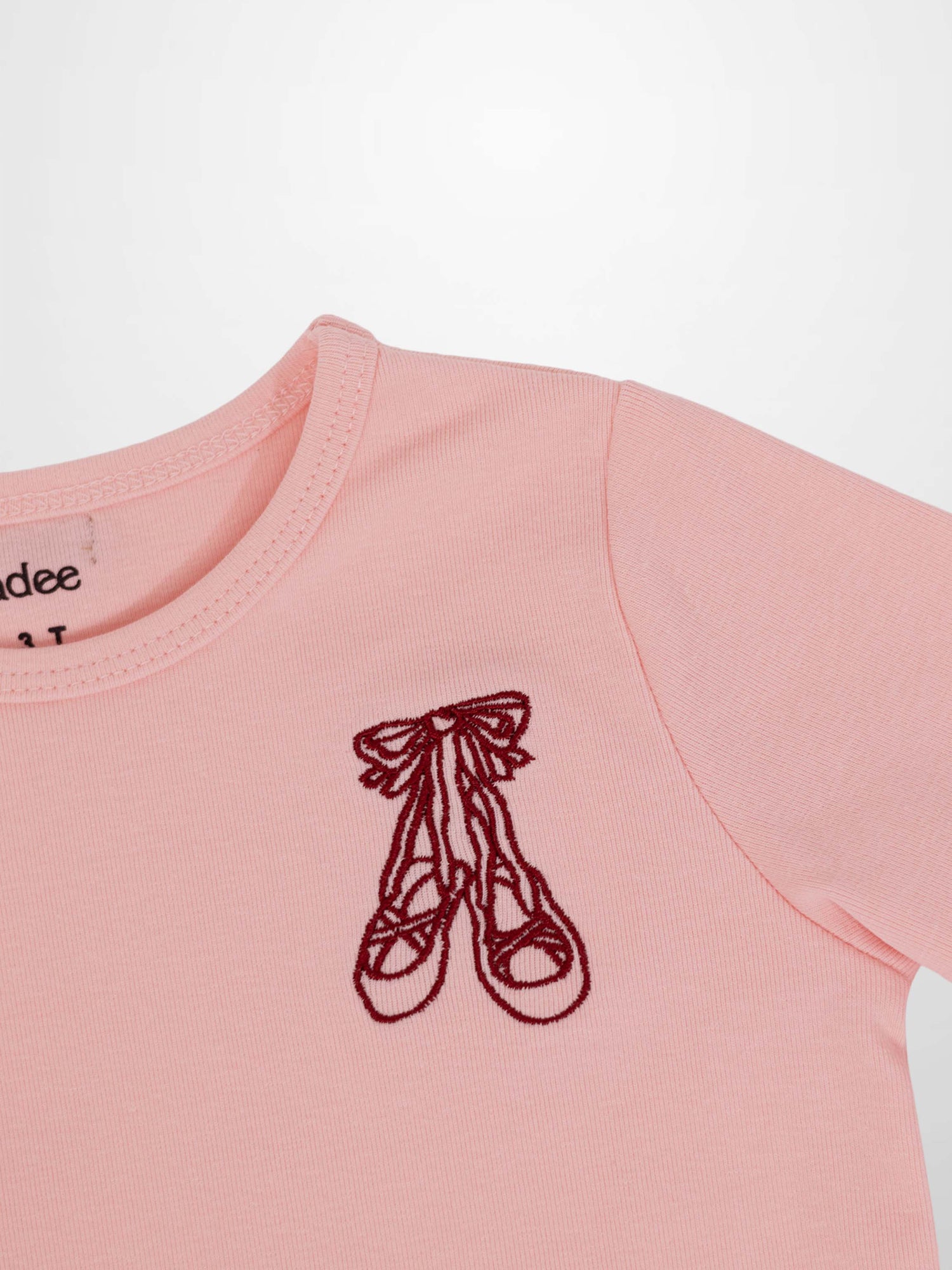 Light pink 3/4 sleeve T-shirt with burgundy ballet slippers emblem on chest.