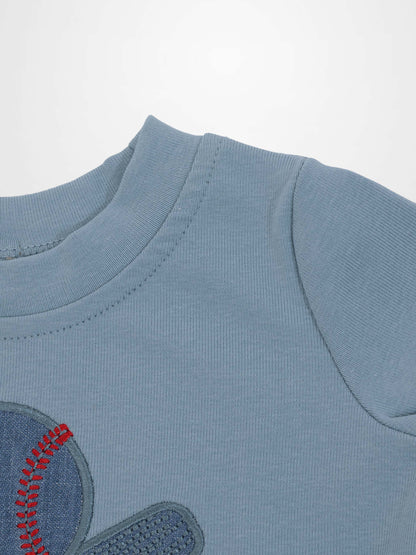 Light blue baseball T-shirt with an embroidered patch featuring red stitching.