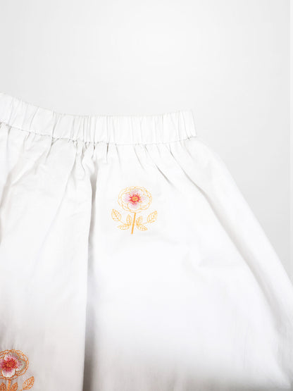 Adee Embroidered Flower Skirt for girls, white fabric with orange flower embroidery and elastic waistband.