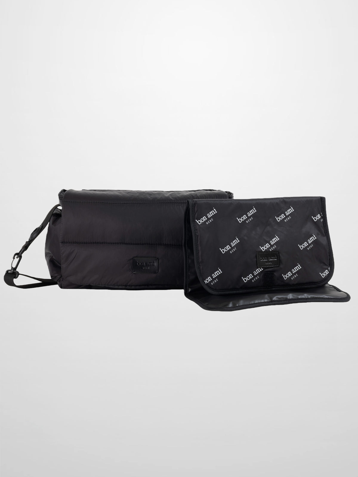 Black padded diaper bag with foldover flap and detachable shoulder strap for modern parents.
