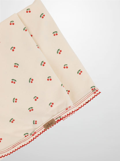 Red Cherry swaddle blanket for girls by Adee with lace trim on cream fabric and scattered cherries.
