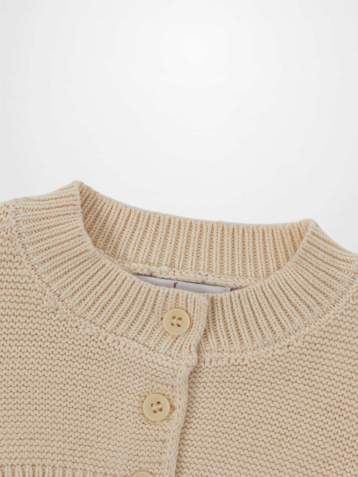 Cropped ivory knit cardigan with ribbed crewneck and button front, unisex dressy top.