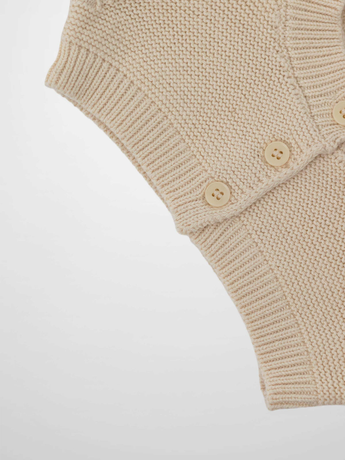 Cropped ivory cardigan by Adee; unisex dressy knit with ribbed cuffs and cream buttons