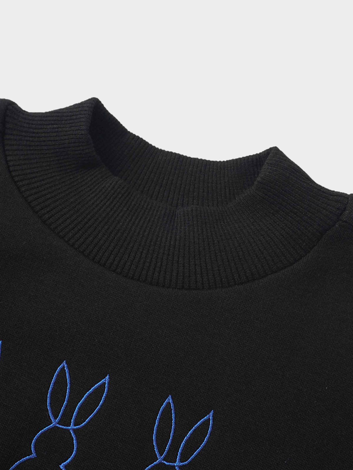Blue bunny embroidery on a black sweatshirt near the ribbed neckline.