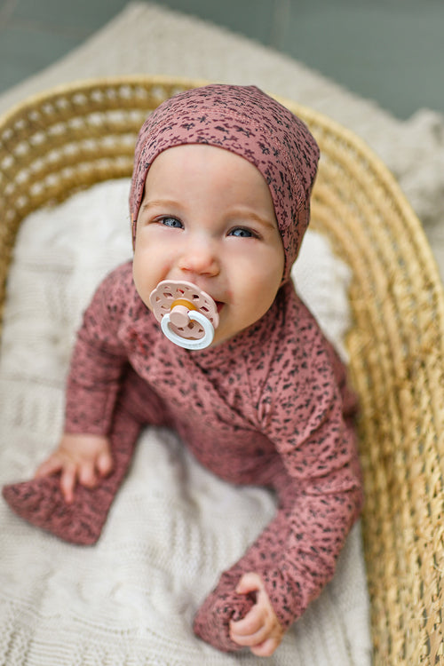 baby girl wearing a jumpsuit footie with roses pattern print and a beanie hat