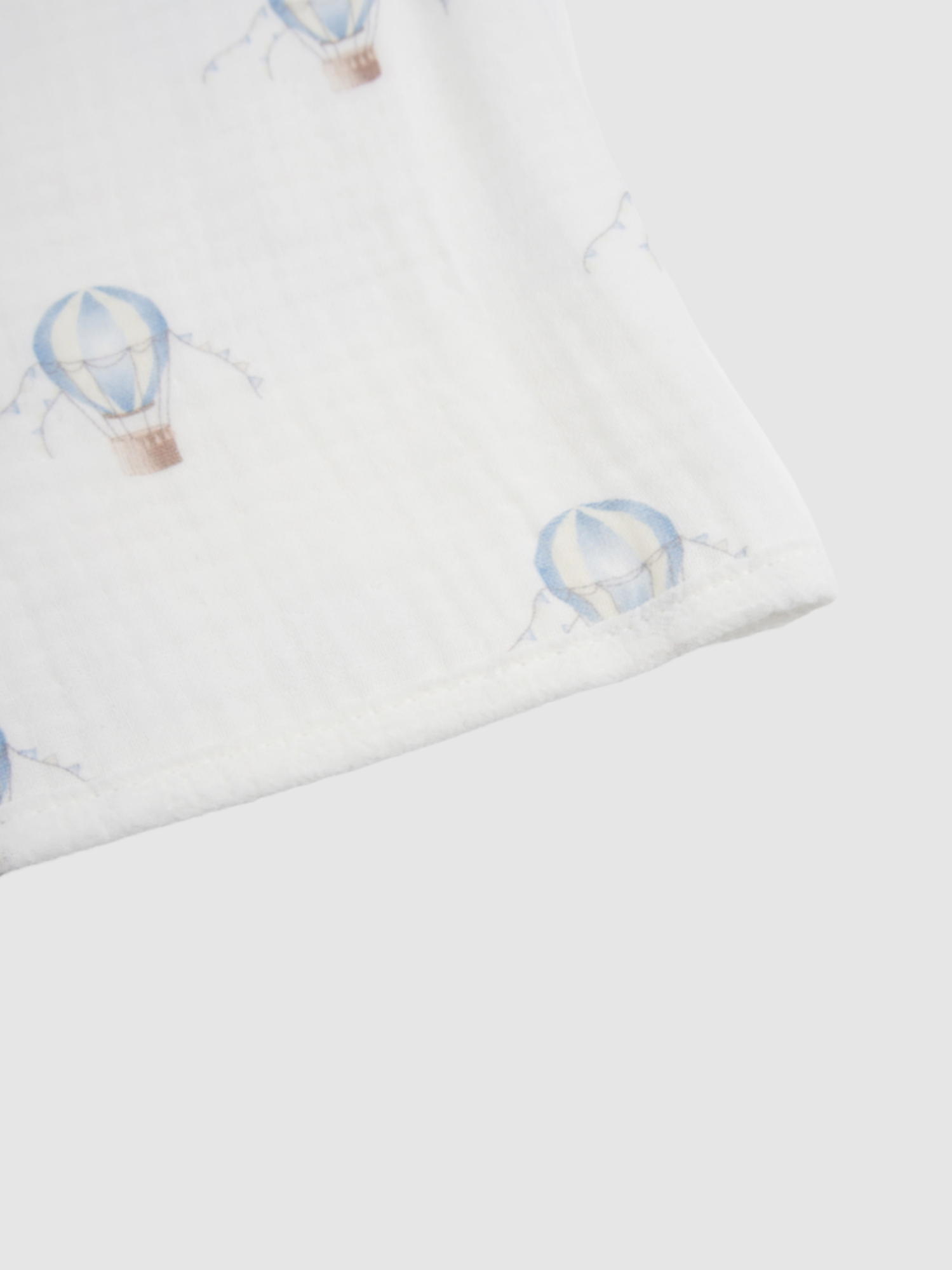 Blue Balloon Blanket swaddle for boys featuring a light-blue balloon pattern on white fabric with a stitched edge