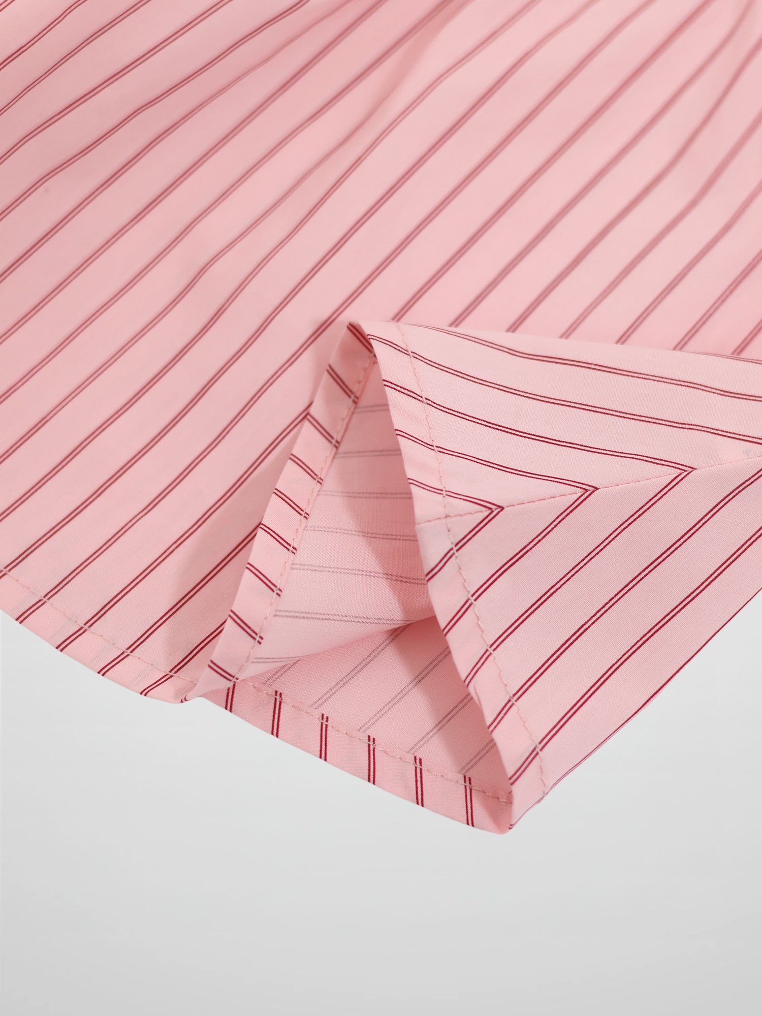 Pink striped cotton skirt with red lines, fabric folded at hem.