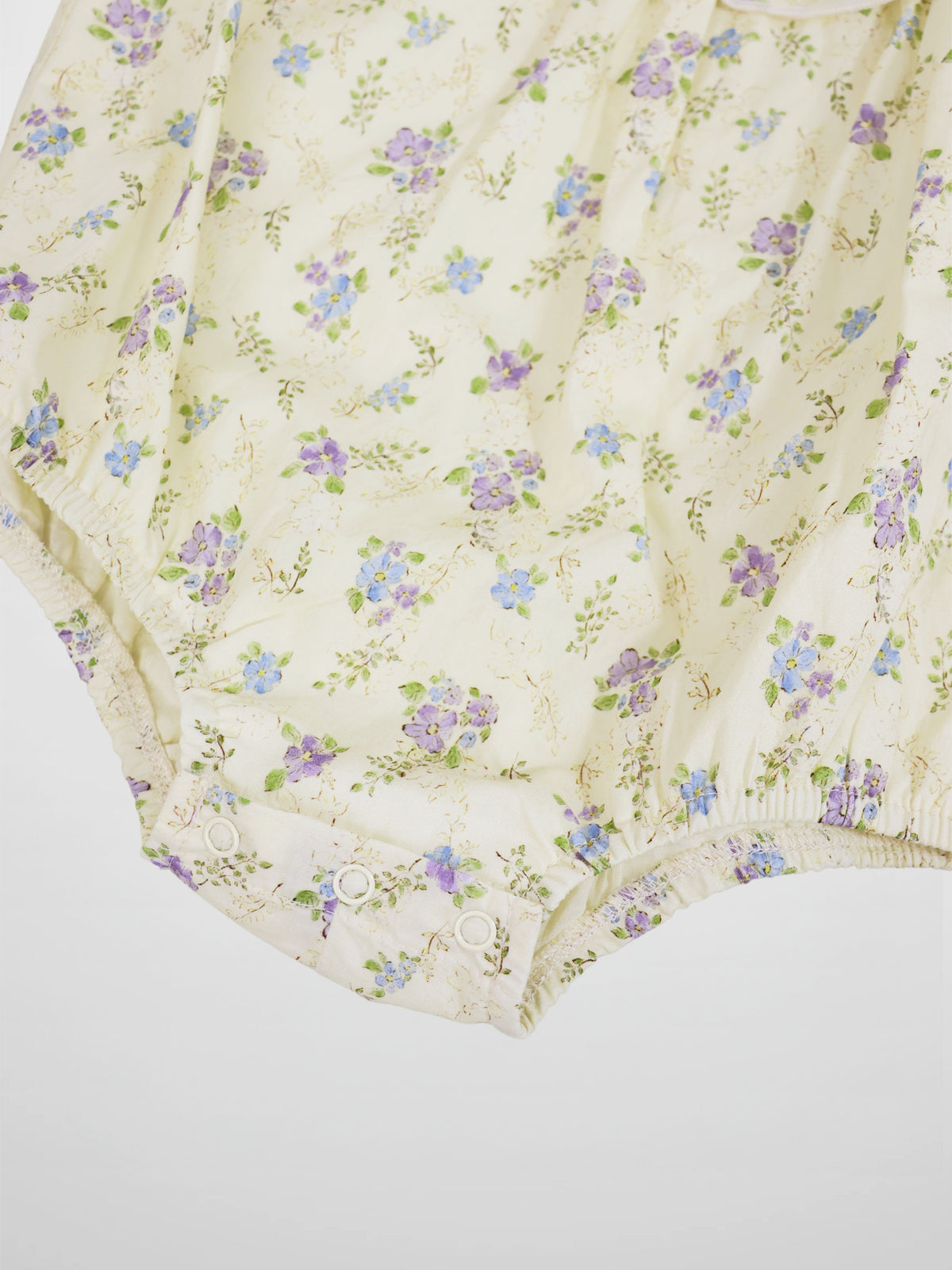 Ivory Flower Romper by Adee; girls dressy romper in cream with purple and blue floral print, snap closures.