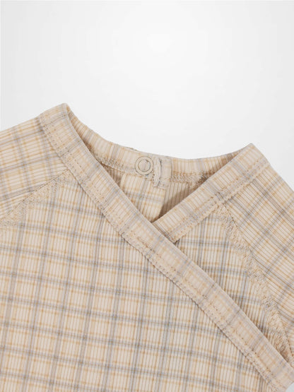 Oatmeal grid-pattern baby jumpsuit in beige with light blue plaid, crossover neck and back snap.