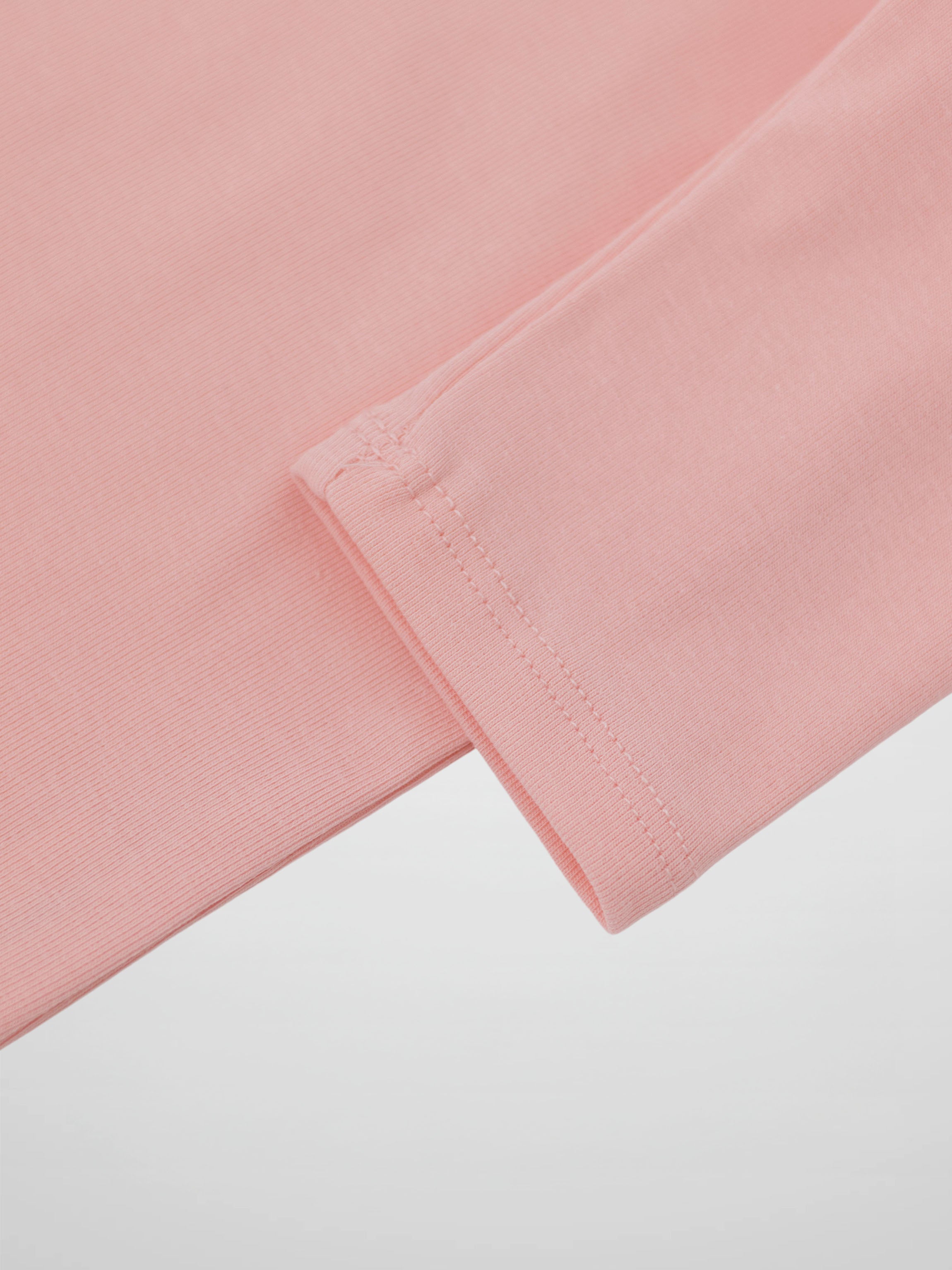 Close-up of light pink 3/4 sleeve T-shirt cuff with stitching.