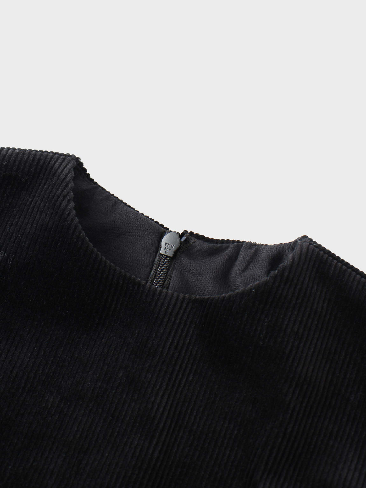 Close-up of a black corduroy jumper neckline with a back zipper.