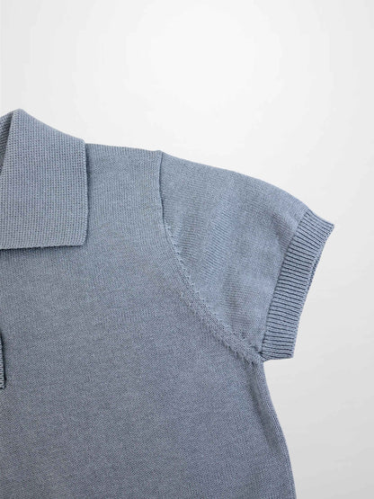 Light blue knit sweater shoulder close-up with ribbed sleeve cuff and polo collar.