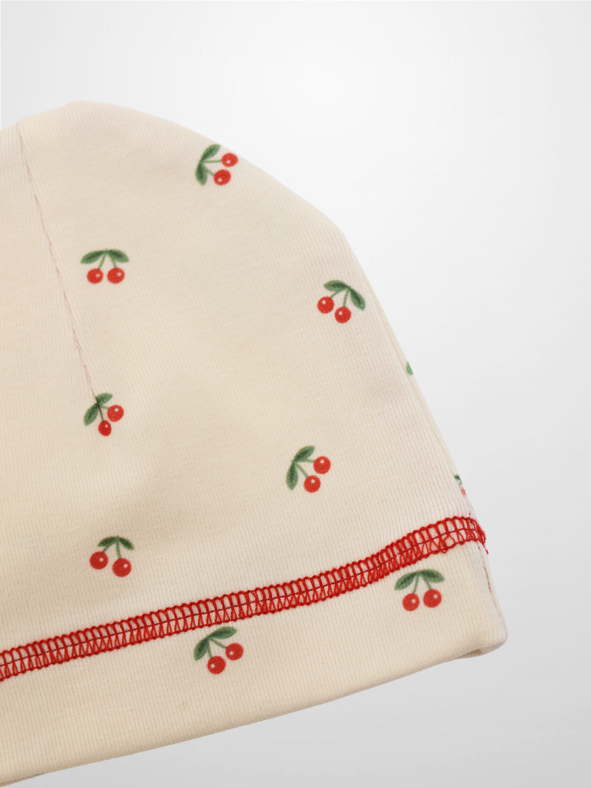 Red Cherry Hat for girls by Adee; beige knit beanie with scattered red cherries and red stitched edge.