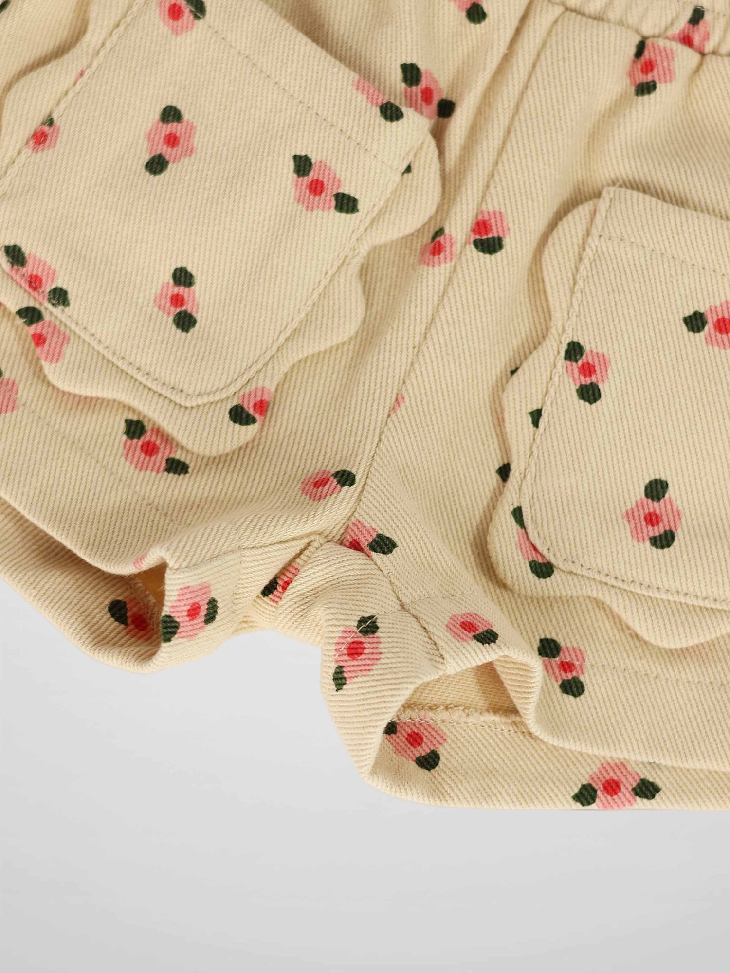 Tan floral shorts with pink blossoms and green leaves, corduroy fabric, front pockets.