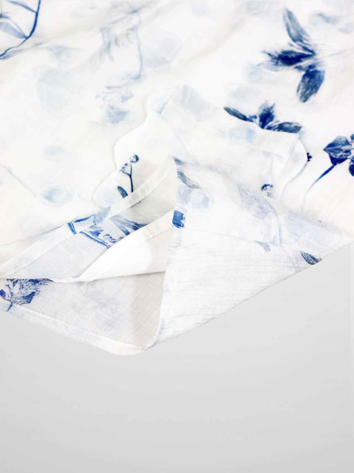 Blue flower jumper dress for girls; white fabric with soft blue florals and light texture, as seen in close-up.