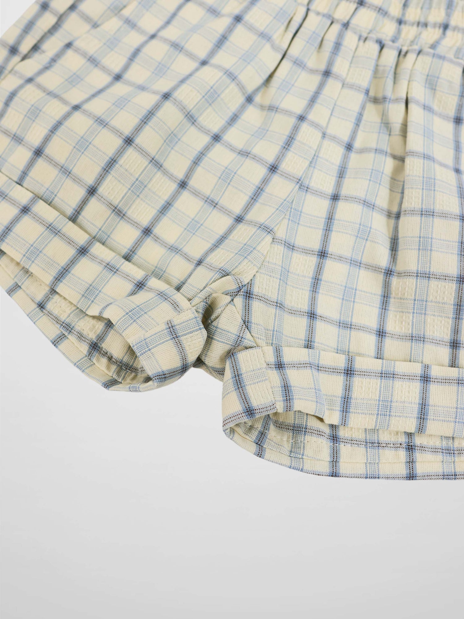 Cream plaid shorts with blue checks and rolled cuffs.