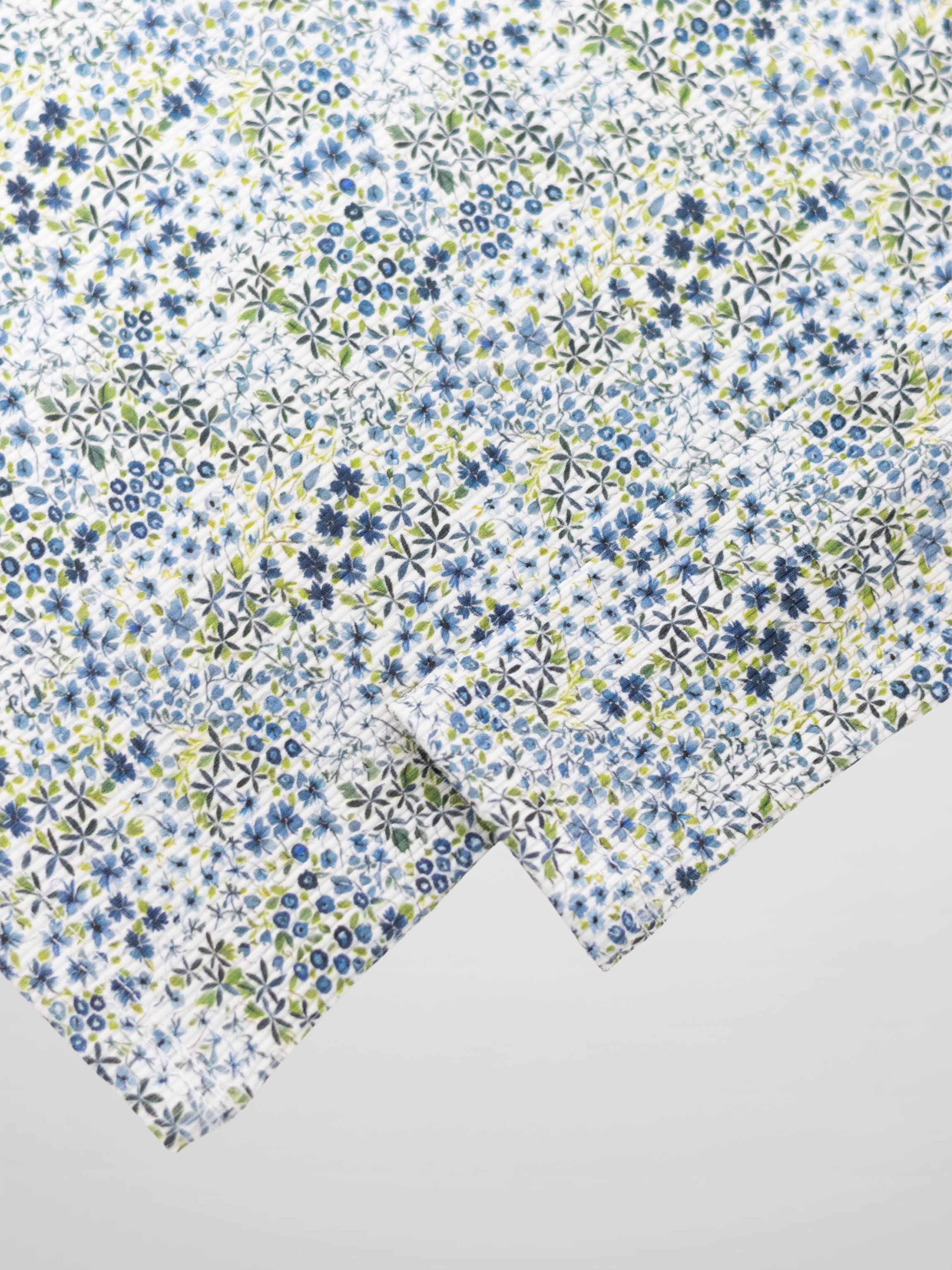 Blue floral pajama fabric with tiny blue and green blossoms on white.