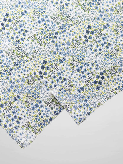 Blue floral pajama fabric with tiny blue and green blossoms on white.