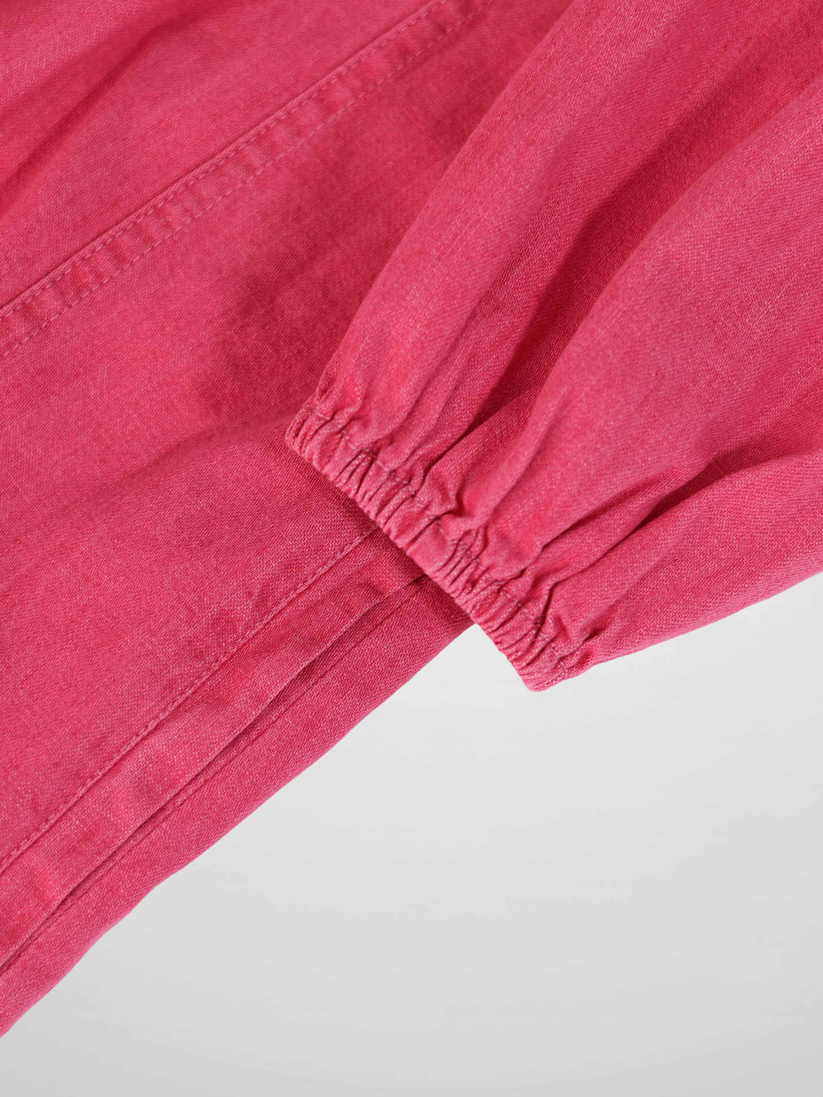 Pink denim 3/4 sleeve dress close-up showing elastic cuff and seam detail.