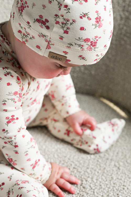 baby girl wearing a beanie hat with jumpsuit footie with pink and red roses