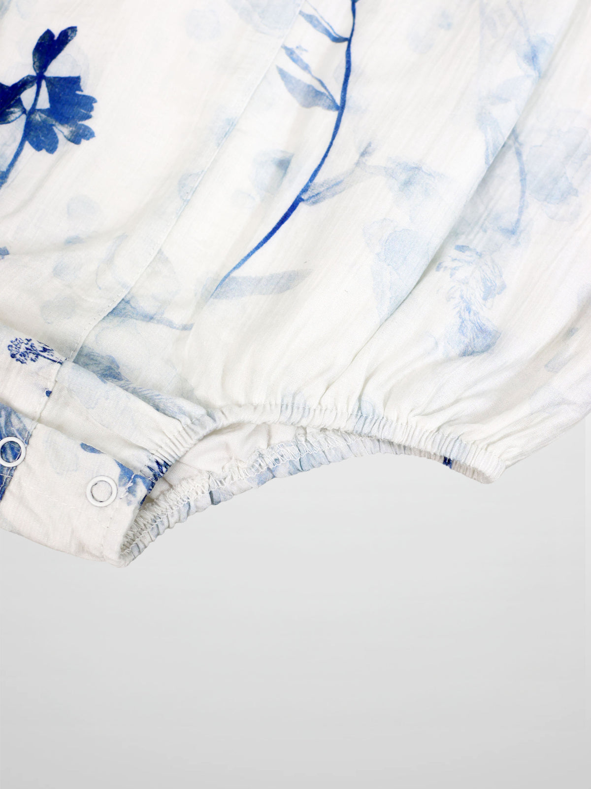Blue Flower Romper for girls by Adee, dressy white fabric with blue floral print and snap closures.