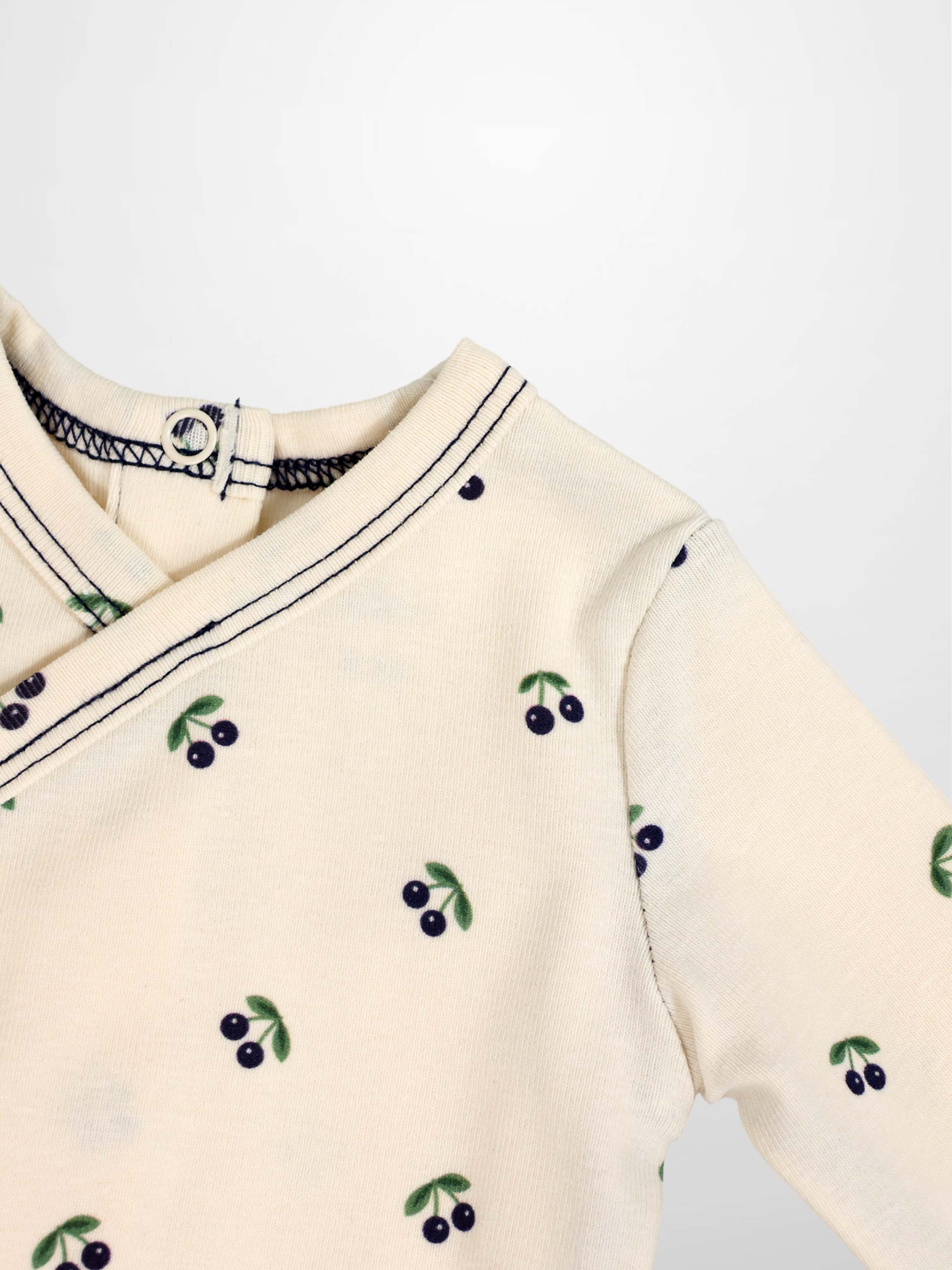 Boys Stretchies beige top with blue cherry print on green leaves and navy trim.