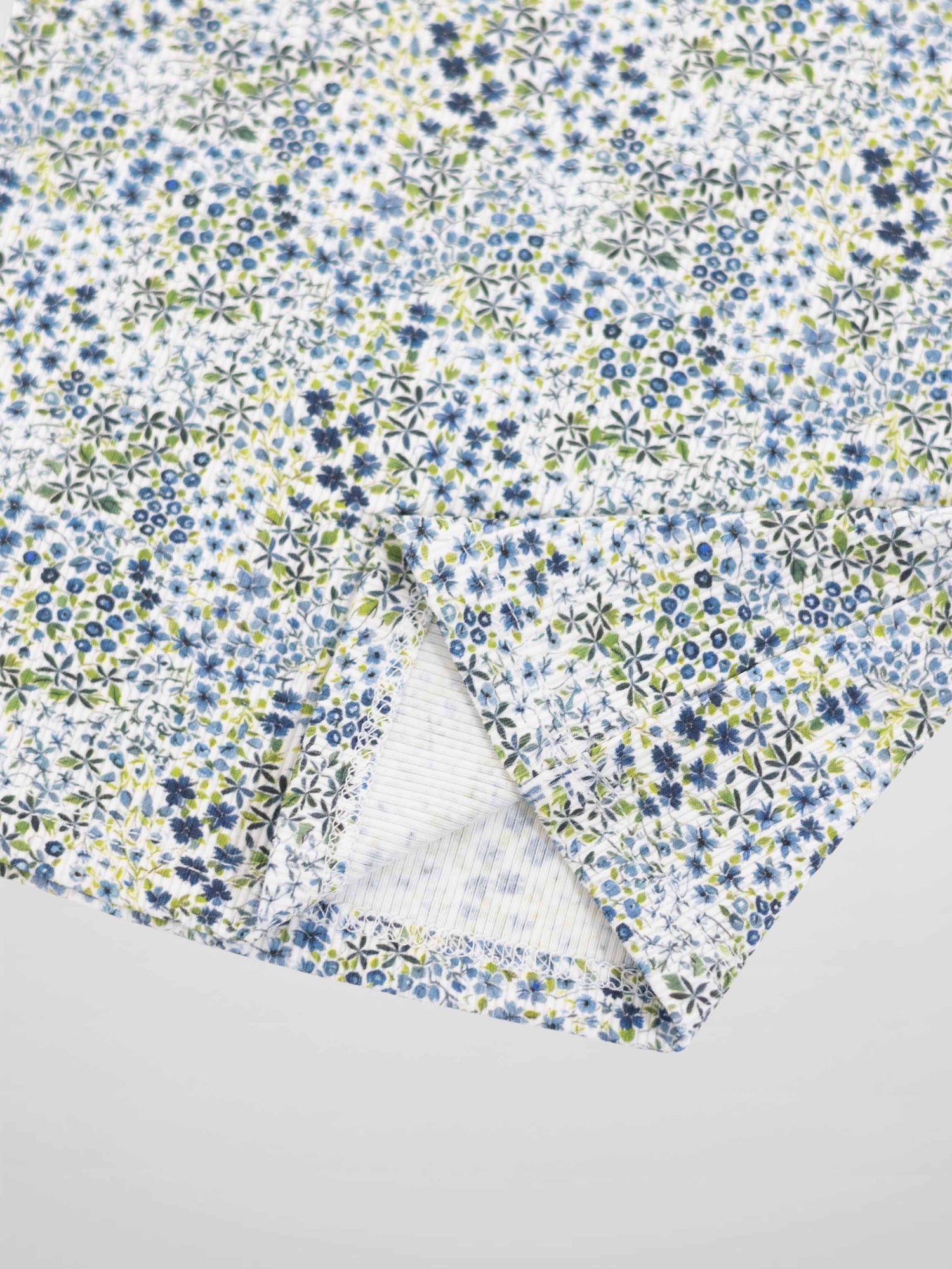Blue floral pajama fabric with tiny blue and green flowers on white background.