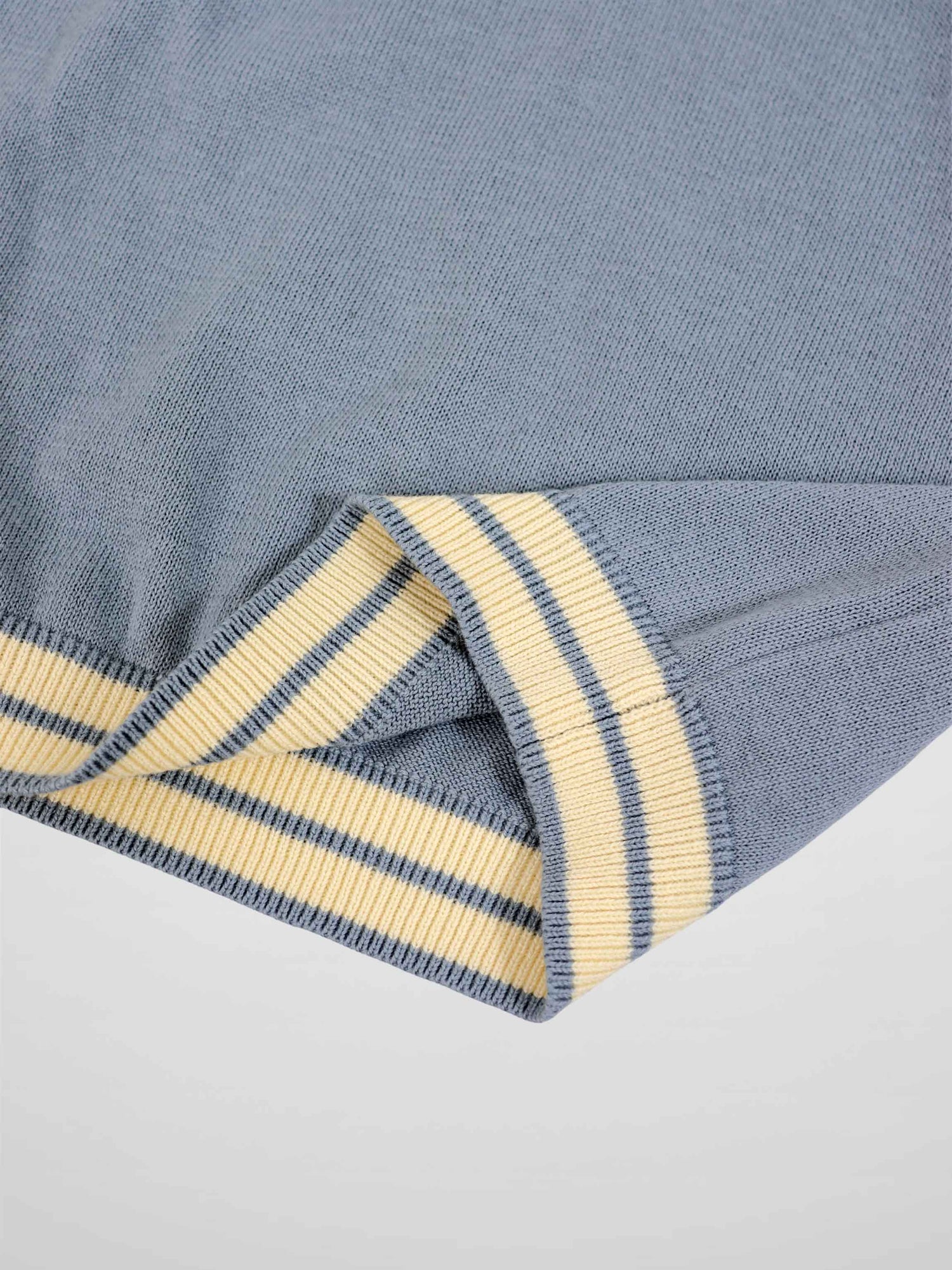 Light blue knit sweater sleeve with cream and navy striped ribbed cuff.