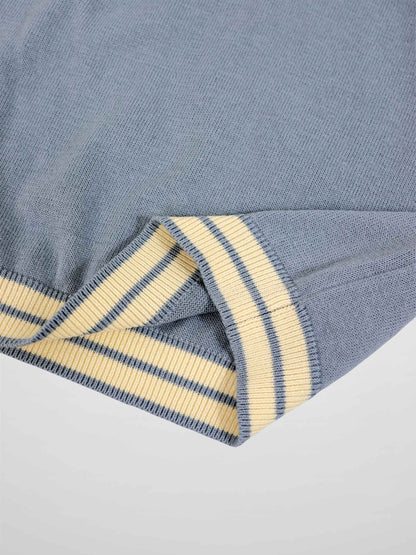 Light blue knit sweater sleeve with cream and navy striped ribbed cuff.