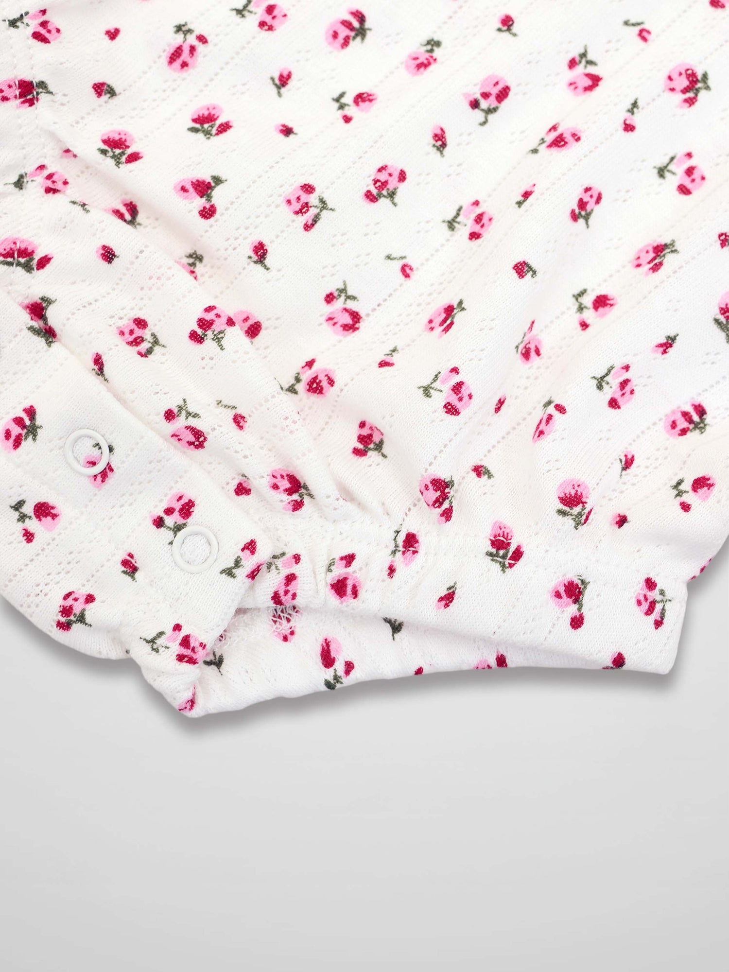 Pointelle floral romper, white with pink blossoms, snap closures.