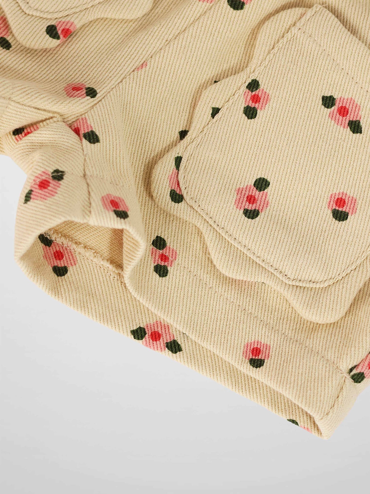 Tan floral shorts fabric with small pink flowers and green leaves, pocket detail visible