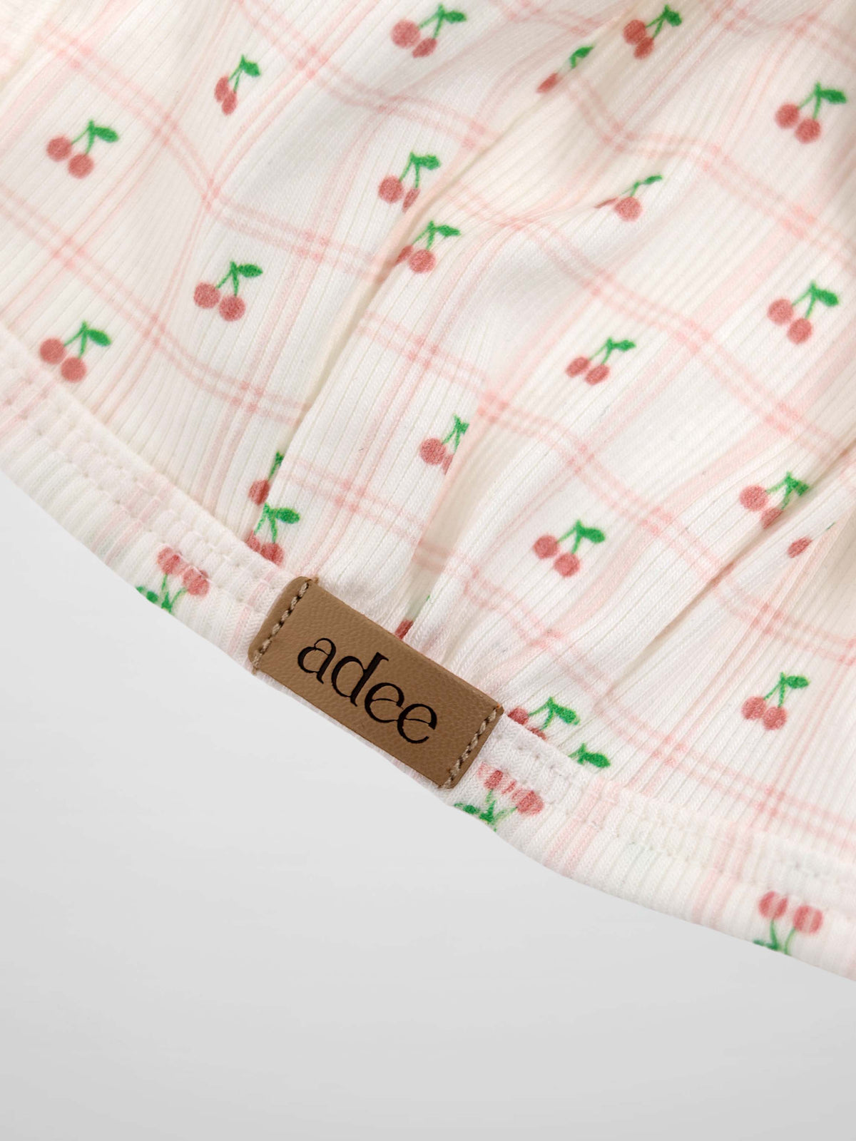 Cherry Window Bonnet for girls by Adee; pink cherry-print on light ribbed fabric with brand tag.