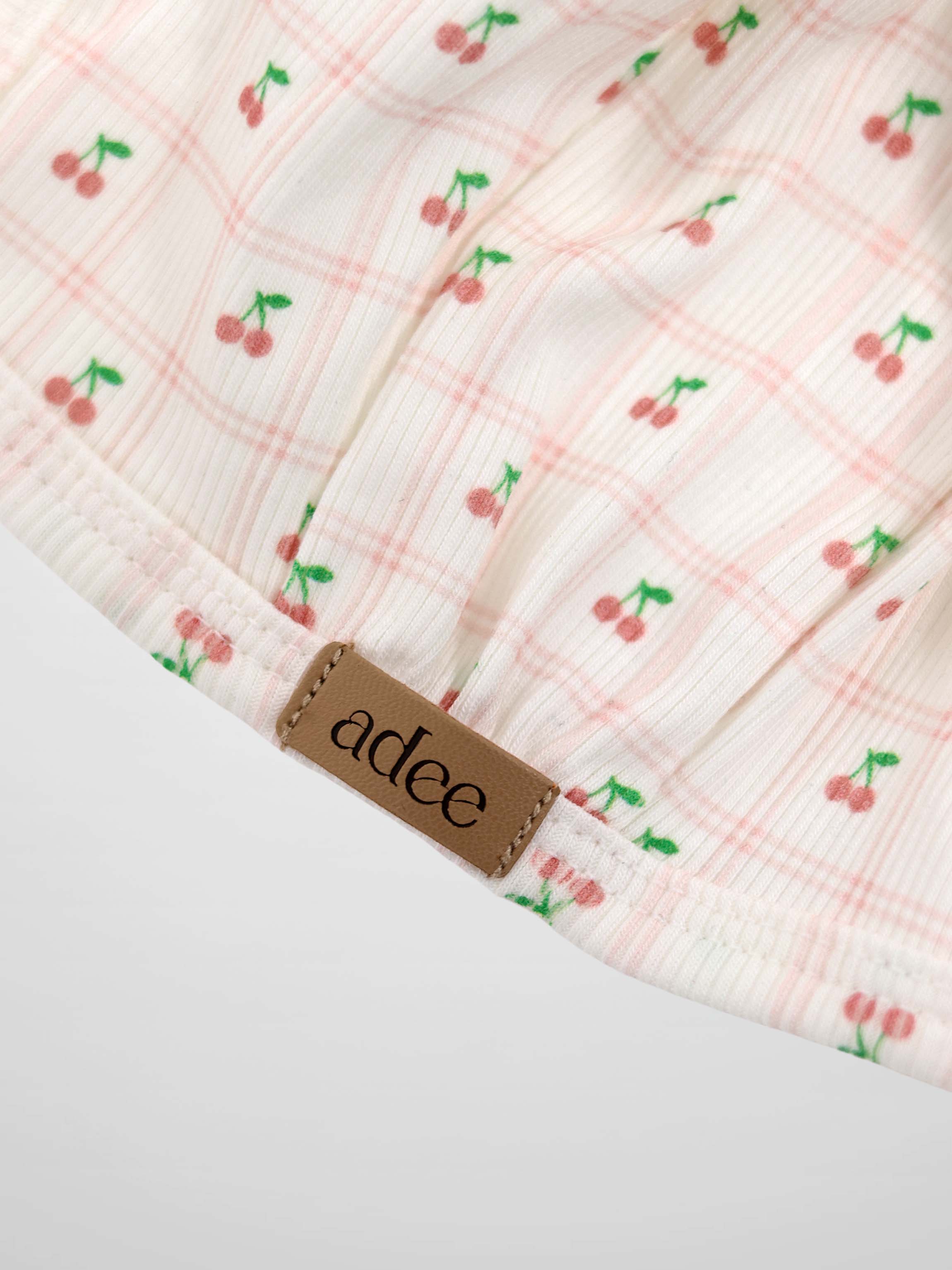 Cherry Window Bonnet for girls by Adee; pink cherry-print on light ribbed fabric with brand tag.