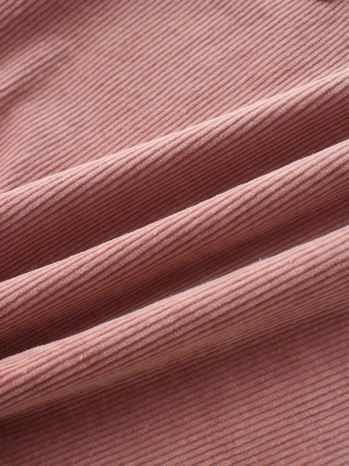 Close-up of mauve corduroy jumper fabric with soft, textured ridges.