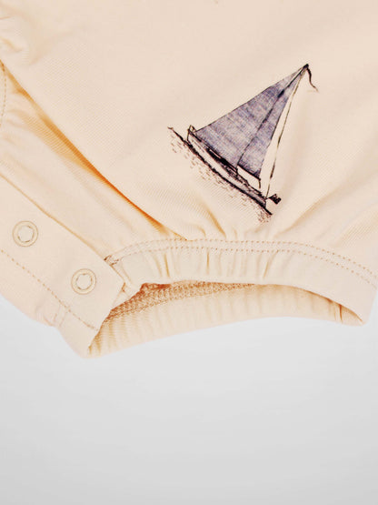 Sail Boat Romper for boys in peach with a sailboat graphic and snap closures.