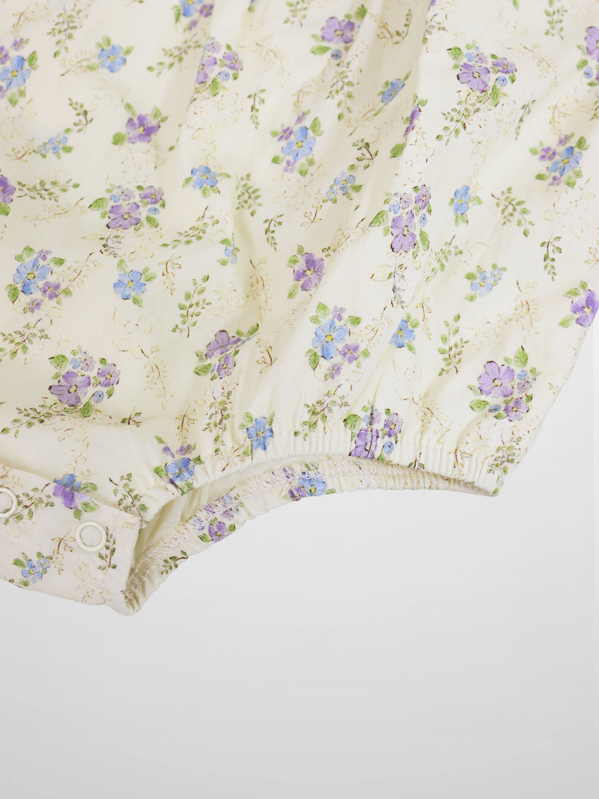 Ivory flower-print girls romper by Adee, dressy style with pastel purple and blue florals.