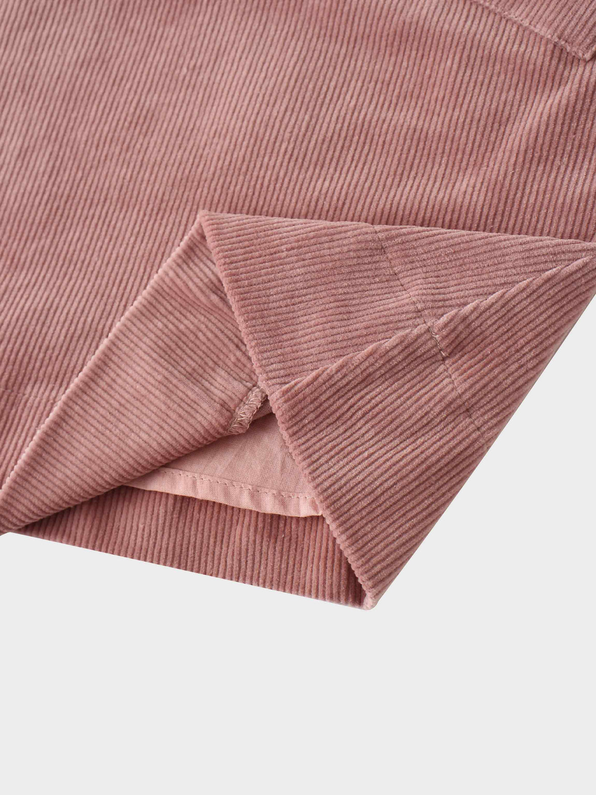 Close-up of mauve corduroy fabric with ribbed texture and folded sleeve cuff.