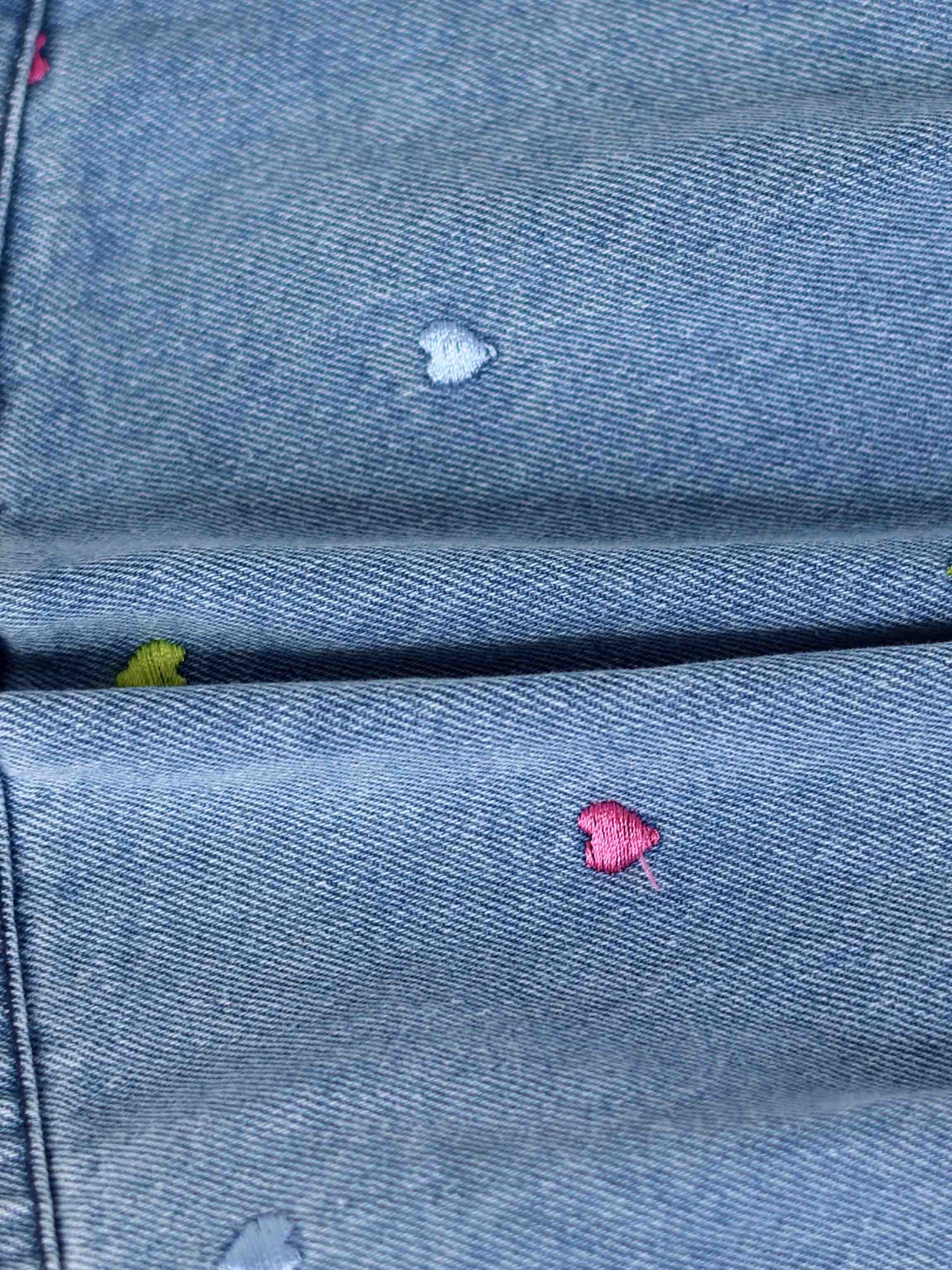 Blue denim fabric with small multicolor embroidered hearts.