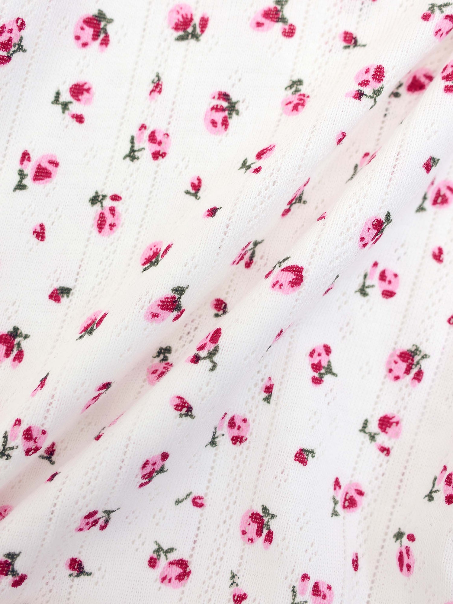 Pointelle Floral Romper for girls; white knit fabric with small pink flowers.