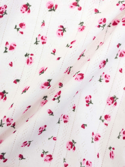 Pointelle Floral Romper for girls; white knit fabric with small pink flowers.